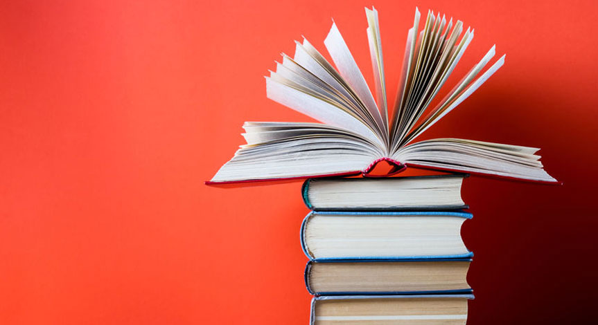 An open hard cover book on top of 4 other closed books with a red background.