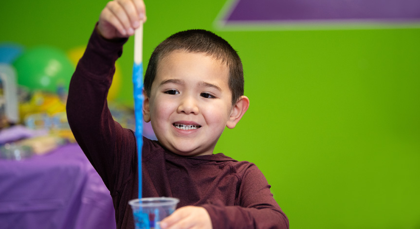 Boy playing with slime in an Activity Cup that he made at a birthday party.
