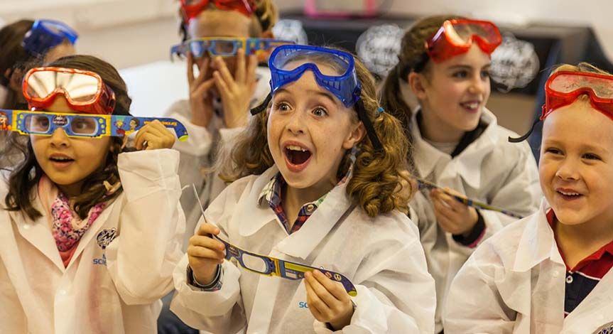 a group of amazed kids wearing diffraction glasses