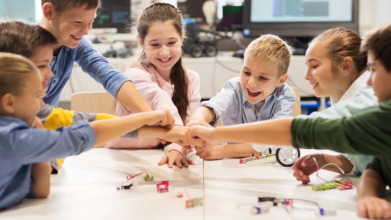 Kids building robots and fist bumping
